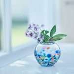 藍色津輕玻璃球形花插花瓶裡放著花，放在窗邊很漂亮