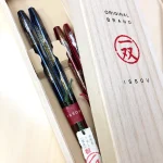 Issou 一雙煙火若狹塗夫婦對筷放在木禮盒裏面，蓋子半打開放在盒子上。