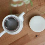 白色bico 美濃燒平蓋茶壺 打開蓋放在枱上的俯視圖，可以看見裏面的隔茶網