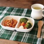 Studio M’ Aeroport 雙格餐盤裡面裝着意大利粉和蔬菜放在格子紋枱布上，餐盤旁邊放了一個匙羹及一杯飲品。