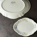 一個小的Studio M’ Mignardises 餐盤放在大的餐盤旁邊,大的底向上,小的面向上放在枱上的俯視圖。