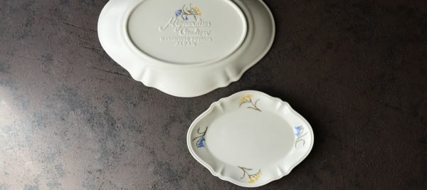 一個小的Studio M’ Mignardises 餐盤放在大的餐盤旁邊,大的底向上,小的面向上放在枱上的俯視圖。