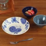 空的 MYSA 藍色虎紋貓花朵碟子擺放在桌面上，旁邊有其他碗。 An empty MYSA blue tiger-striped cat flower plate placed on a tabletop, alongside other bowls.