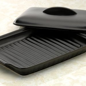 日本製造陶瓷烤盤的耐熱蓋半開，擱放在盤邊，清晰可見內部底部的設計。 Close-up of the Japanese-made ceramic baking tray with the heat-resistant lid half open, resting at the edge, revealing the inside bottom of the tray.