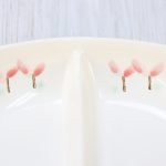 位於美濃燒橢圓2格餐盤邊緣的粉色花朵圖案特寫. Close-up of pink flower patterns on the edge of a Mino Ware oval two-compartment plate.