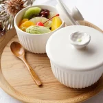 兩個Yoshizawa 益子燒茶碗蒸杯放在圓形托盤上,一個蓋著蓋子,另一個打開顯示裡面的甜點 - Two Yoshizawa Mashiko-style chawanmushi cups on a round tray, one covered with a lid and the other open revealing the dessert inside.