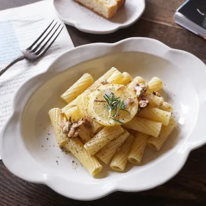 Yoshizawa 益子燒雲邊深盤上放著義大利麵，擺放在桌上，清楚展示雲朵設計的邊緣 - Yoshizawa Mashiko-style cloud-edged deep plate with pasta on it, placed on a table, clearly showing the cloud design edge