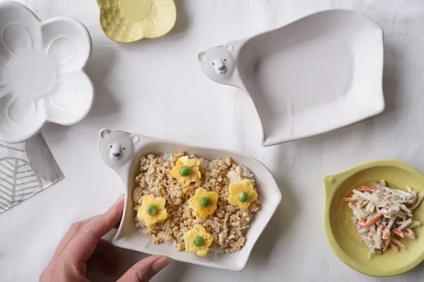 俯視圖，兩個Yoshizawa 益子燒北極熊小碗，一個有食物，另一個空著，清楚可見形狀。 / Top view of two Yoshizawa Mashiko-style polar bear bowls, one with food and one empty, clearly showing their shape.