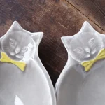 兩個Yoshizawa 益子燒黃蝶結貓碗的頭部特寫，展示貓的頭部和脖子上的黃色蝴蝶結 - Close-up of the heads of two Yoshizawa Mashiko-style yellow bow tie cat bowls, showing the cat heads and the yellow bow ties around their necks.