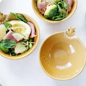 三個Yoshizawa 益子燒松鼠碗放在桌上，前面的碗是空的，設計清晰可見，後面的兩個碗裡裝有沙拉 - Three Yoshizawa Mashiko-style squirrel bowls on a table, with the front bowl empty and the design clearly visible, while the two back bowls contain salad.