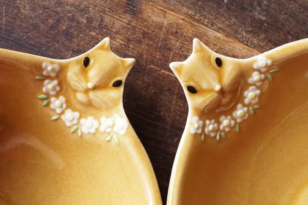 兩個兔子造型餐盤的頭部特寫,展示設計細節和兔子佩戴的粉紅色花朵項鍊 - Close-up of the heads of two rabbit-shaped plates, showing design details and the pink flower necklace the rabbits are wearing.