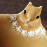 Yoshizawa 益子燒松鼠碗的頭部特寫,清楚展示頭部細節和粉紅色花朵項鍊 - Close-up of the head of a Yoshizawa Mashiko-style squirrel bowl, clearly showing the head details and the pink flower necklace.