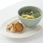 淡綠色杯子裝着飲料放在茶點碟上