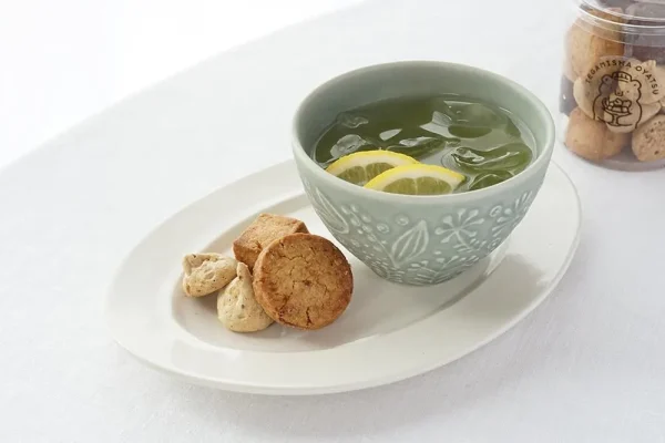 淡綠色杯子裝着飲料放在茶點碟上