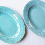 兩個Yoshizawa 益子燒綠色兔子花卉橢圓餐盤並排，左側較淺，右側較深，展示手工產品的獨特性 - Two Yoshizawa Mashiko-style green rabbit floral oval plates side by side, left lighter and right darker, highlighting the uniqueness of each handmade piece.