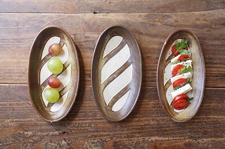 三個Yoshizawa 益子燒法式面包椭圆盤並排,左側有水果,中間空盤,右側有甜點 - Three Yoshizawa Mashiko-style oval French bread plates side by side: fruit on the left, empty in the middle, dessert on the right.