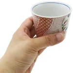 展示一隻手握著赤繪蕎麥碗，清晰顯示碗的設計和手的握持方式. An image showing a hand holding the 赤繪蕎麥碗, clearly displaying the bowl's design and the way it is held.