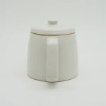 色 Ancient Pottery 日本製壺的側面視圖，展示把手的設計. Side View of a White Japanese Teapot Highlighting the Handle Design.