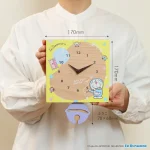 雙手握著日本製的哆啦A夢木掛鐘,顯示鐘面的正面,圖片上標示了鐘的尺寸. Holding the Japanese-made Doraemon Wooden Wall Clock with both hands, showing the front of the clock, with measurements marked on the picture.