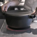 雙手拿着放在電磁爐上面的日本製 OVJECT 鑄鐵兩用深型鍋的手柄