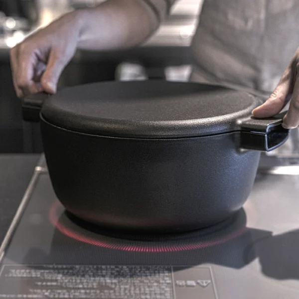 雙手拿着放在電磁爐上面的日本製 OVJECT 鑄鐵兩用深型鍋的手柄