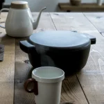 日本製 OVJECT 鑄鐵兩用深型鍋蓋上蓋子與其他餐具一起放在木枱上