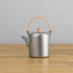 相澤工房 BP直筒茶壺 - 弦手柄款式，茶壺嘴向左邊放在木枱上的展示筒