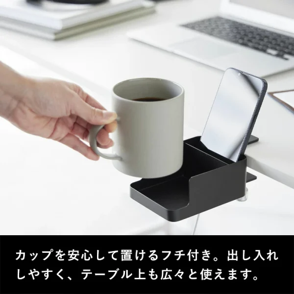 手拿着一杯飲品準備放上裝在枱邊的黑色的日本 TOWER 杯夾架