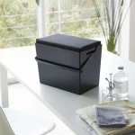 黑色款的 TOWER 熨斗收納箱放在房間的白色枱面上，背景可見窗外景色