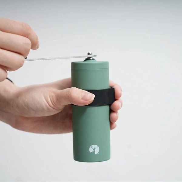 手上拿着日本製 CAPTAIN STAG 陶瓷刀手搖咖啡研磨器，示範示範攪磨咖啡豆的白色背景圖