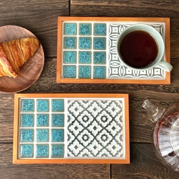 兩款不同設計的日本製 SATOMIMI 咖啡托盤放在木枱上，其中一款上面放着一杯咖啡，旁邊有一個裝着麵包的碟與一個咖啡壺