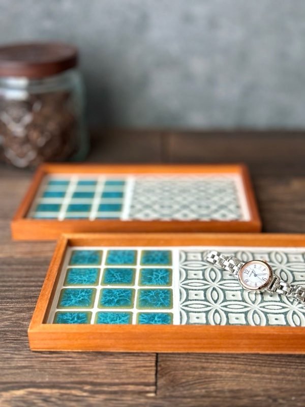 山茶花與手菊款的日本製SATOMIMI 咖啡托盤 放在木枱上的側面圖，前面的手鞠款托盤上放着一隻手錶。