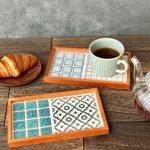 山茶花款與手鞠款日本製SATOMIMI 咖啡托盤一起放在木枱上，旁邊放着一碟牛角包，手鞠款托盤上放在一杯咖啡