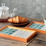 日本製SATOMIMI 咖啡托盤 手鞠款與另一款式的托盤放在木枱上，旁邊有牛角包及咖啡壺等物件