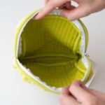 雙手打開miyaco nishio 有機棉絎縫化妝包，展示袋裏面的俯視圖