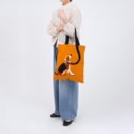 遠距離拍攝的圖片顯示女士手上挽着Maison Bengal|MQ 狗狗手提袋,訊息看到袋子的正面,背景是白色。