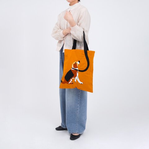 遠距離拍攝的圖片顯示女士手上挽着Maison Bengal|MQ 狗狗手提袋,訊息看到袋子的正面,背景是白色。