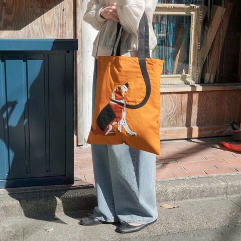 女士手上挽着Maison Bengal|MQ 狗狗手提袋,訊息看到袋子的正面,背景是街景。