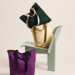 HAY｜Everyday 有機棉手挽袋閂咗顏色兩個放在椅子上，一個放在地下，形成有趣的構圖，背景是米黃色。