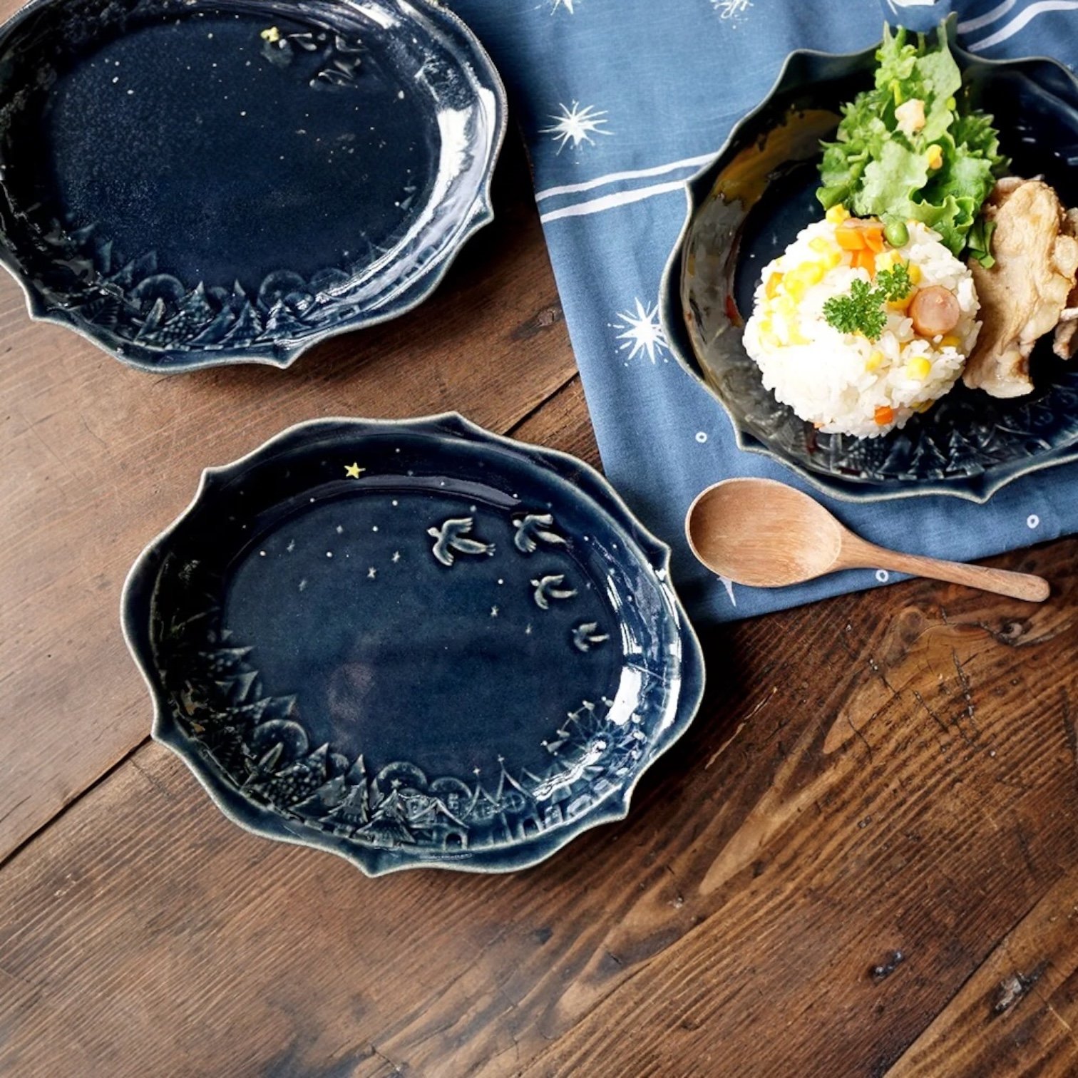 三個Yoshizawa 益子燒橢圓餐盤，一個裝着食物，兩個放在旁邊，一齊放在枱上的場景圖