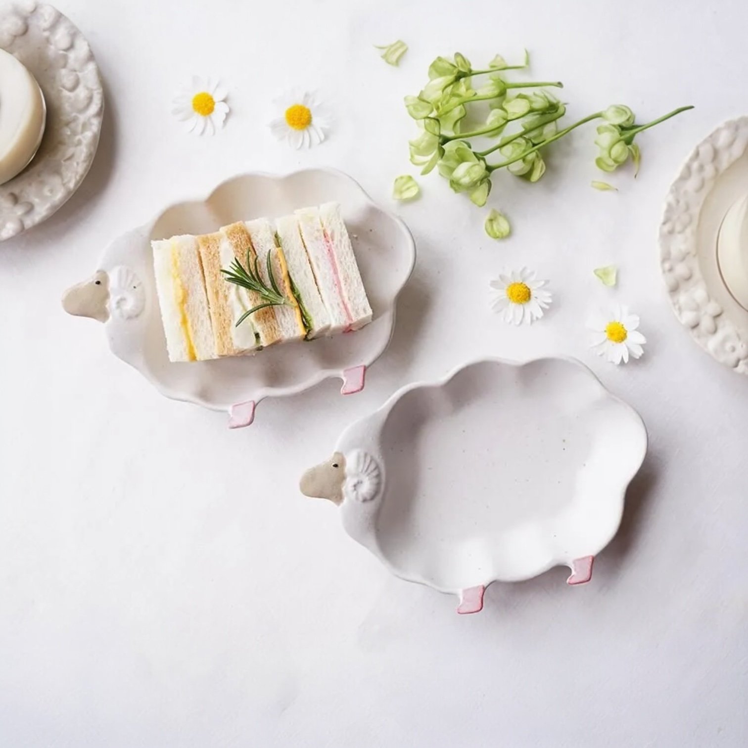 兩個Yoshizawa 益子燒綿羊造型餐盤的正面視圖，一個裡面有三明治，另一個空著 - Front view of two Yoshizawa Mashiko-style sheep-shaped plates, one with a sandwich and the other empty.