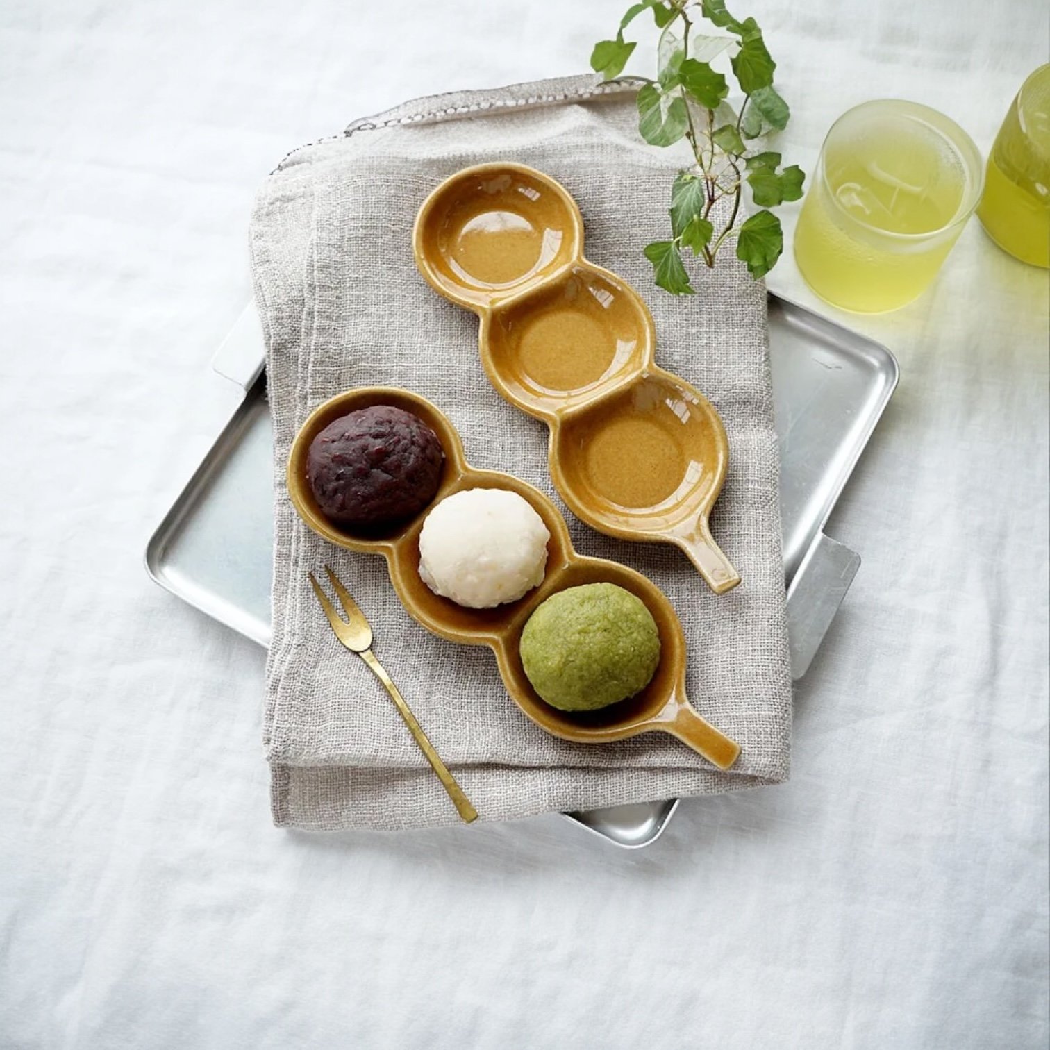 兩個Yoshizawa 益子燒糰子長盤在托盤上，左側有三個糰子，右側空盤 - Two Yoshizawa Mashiko-style dango long plates on a tray, with three dango on the left and the right plate empty.