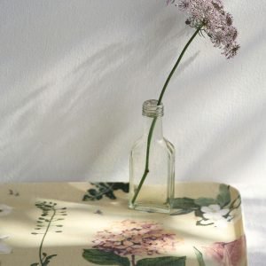 日本製 荻原美里 亞麻面長方形托盤 - Botanical 款放在白色枱面，托盤上面放着一個透明玻璃花瓶，花瓶裏面插這一枝花