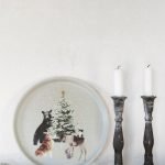 日本製 Fog Linen Work 亞麻面圓形托盤 聖誕限定款放在柜面豎直靠着牆壁，旁邊有二個蠟燭座，上面插着蠟燭。