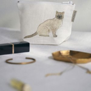 Isabelle Boinot 小貓舟形亞麻小物包放在枱上，前邊有小物件。