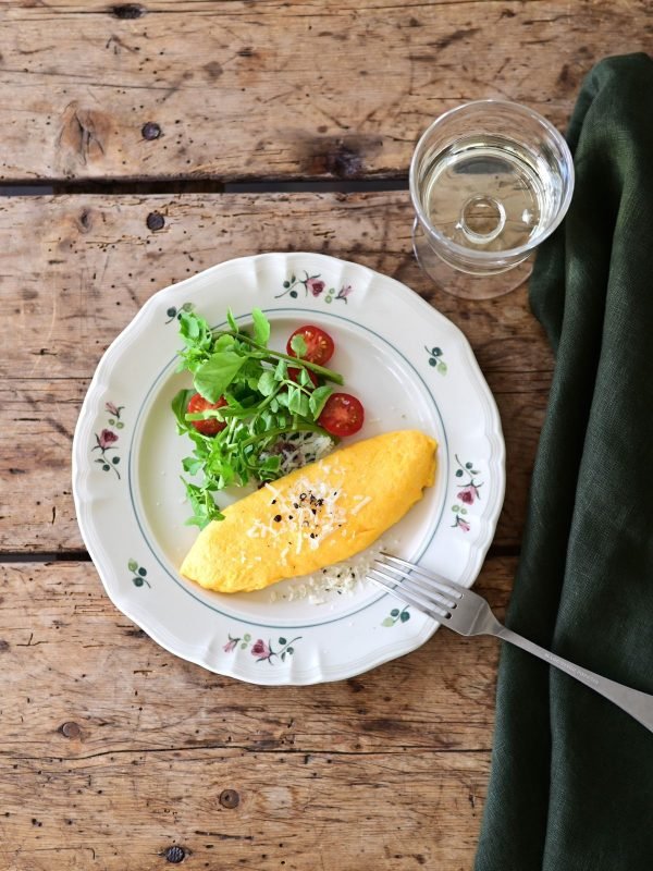 Studio M’ 2025 秋冬新系列 Rosier 圓餐盤裝着食物放在木枱面的俯視圖,旁邊有叉及飲品。