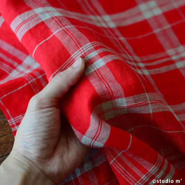 左手拿著Studio M’ Poggio 緋紅色格子布料