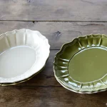 白色與橄欖綠款STUDIO M' Sobokai Communus 饗宴浮雕盤平排放在木枱上的俯視圖