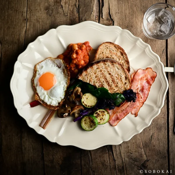 白色款 STUDIO M' Sobokai Communus 饗宴浮雕盤 (32.5cm) 裝着食物放在木餐桌上的俯視圖。