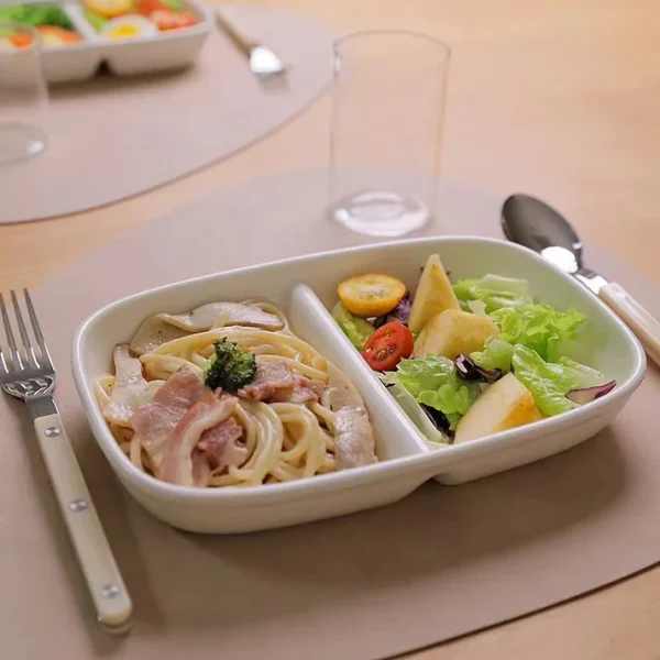 Studio M' Aeroport 雙格盤裝着沙律放在枱上，兩邊各放了一把叉與匙羹。